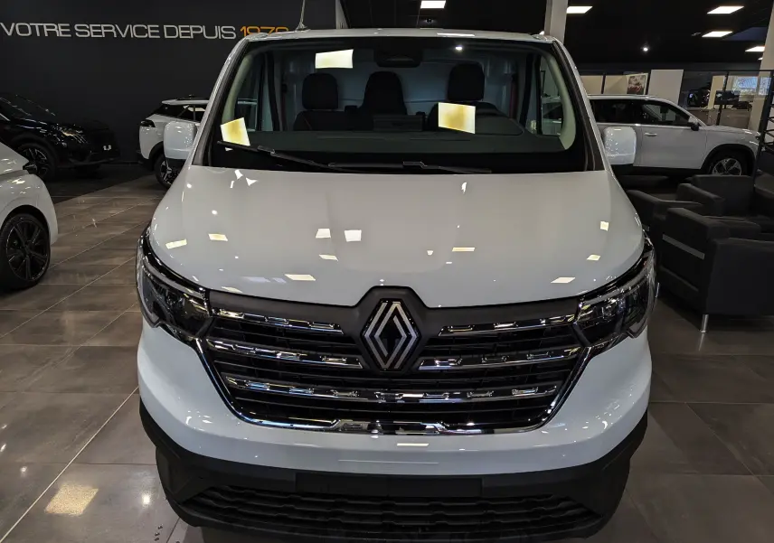 Vue frontale d'un Renault Trafic Fourgon blanc minéral 2025 avec calandre chromée et logo Renault bien visible.