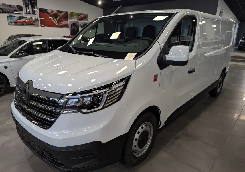 Renault Trafic Fourgon blanc minéral en 3/4 avant droit, avec calandre chromée et feux LED modernes.