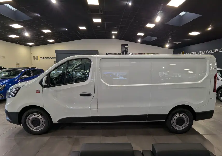 Profil latéral droit du fourgon Renault Trafic L2H1 blanc minéral, avec porte coulissante et jantes acier noires.