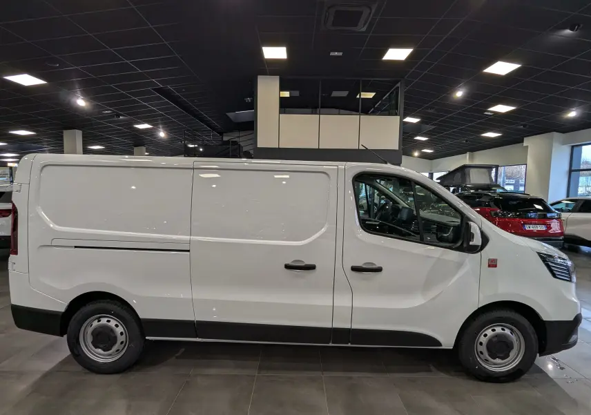 Profil droit d’un Renault Trafic Fourgon blanc minéral 2025, avec portes latérales et jantes acier en showroom.