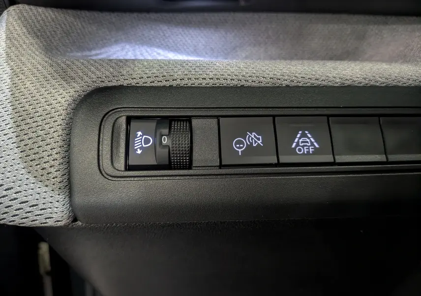 Gros plan sur les commandes d'assistance du tableau de bord d'une Citroën C3 Aircross Hybride 2025, tissu gris visible.