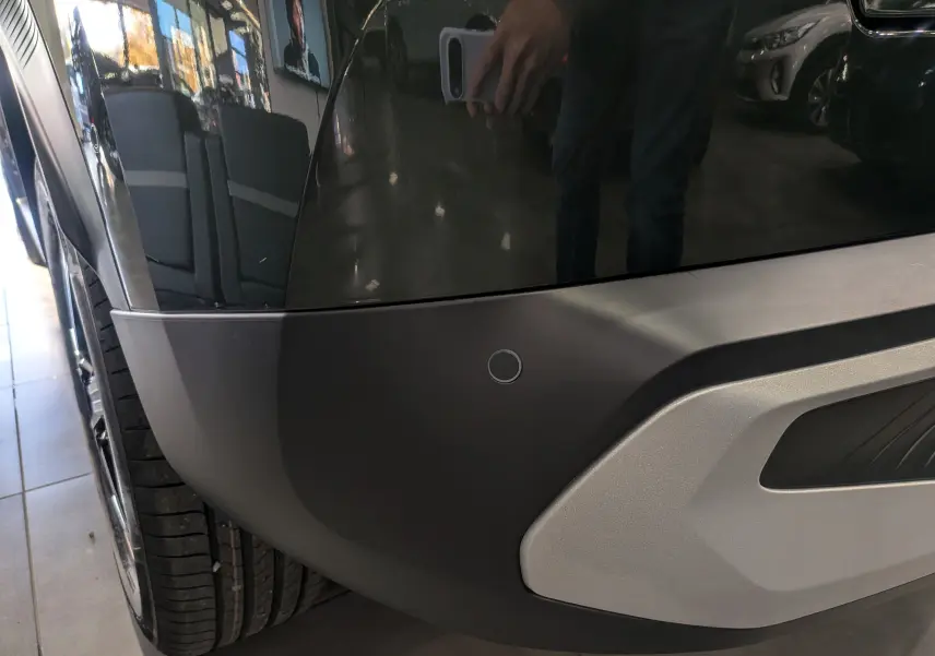 Gros plan sur le pare-chocs arrière gauche noir mat avec capteur de stationnement du Citroën C3 Aircross Vert Montana.