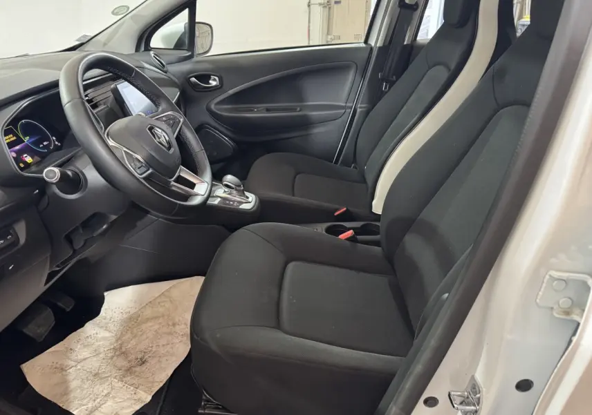 Vue intérieure côté conducteur de la Renault ZOE Business 2020 blanche, avec sièges noirs et volant multifonctions.