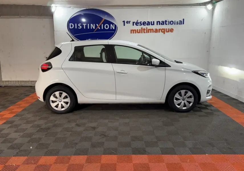 Renault ZOE Business 2020 blanc vue de profil côté gauche dans un garage avec sol noir et orange.