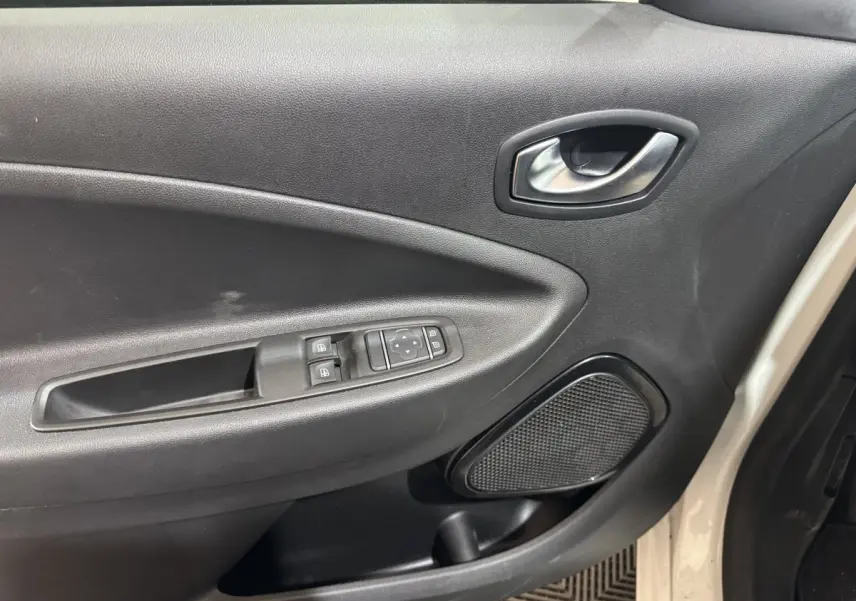 Vue intérieure côté gauche de la porte avant blanche de la Renault ZOE 2020 avec commandes électriques et haut-parleur intégré.
