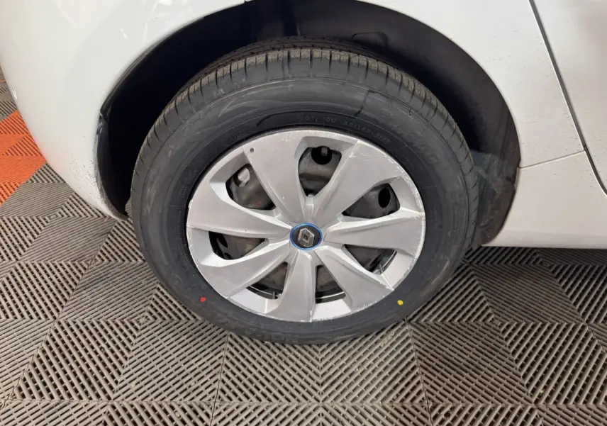 Gros plan sur la roue avant droite blanche d'une Renault ZOE 2020 avec enjoliveur gris et logo Renault central.
