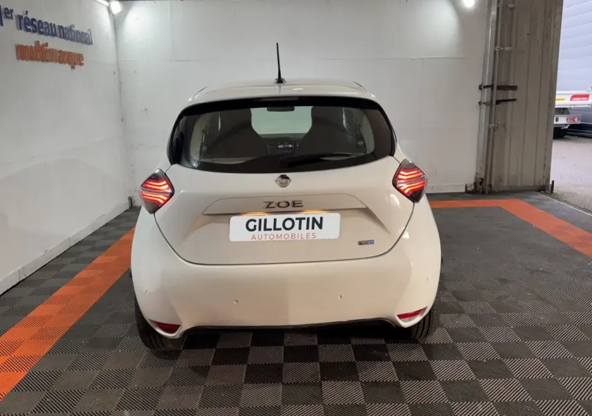 Vue arrière d'une Renault ZOE Business blanche de 2020 avec feux LED allumés, stationnée en intérieur.