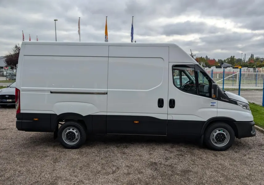 Vue de profil droit d’un utilitaire Iveco Daily blanc avec portes coulissantes et bas de caisse noir.
