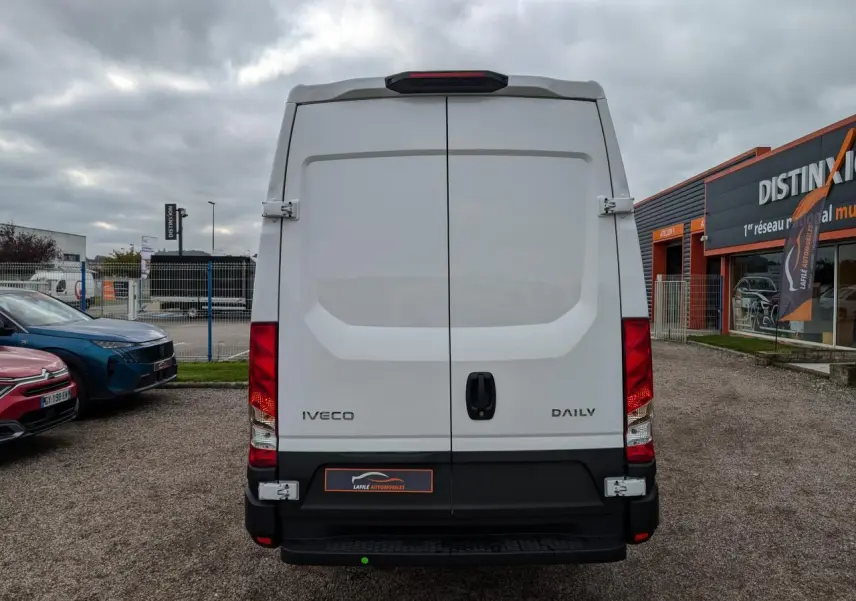 Vue arrière d’un utilitaire Iveco Daily blanc, portes battantes fermées avec poignées noires et feux rouges verticaux.