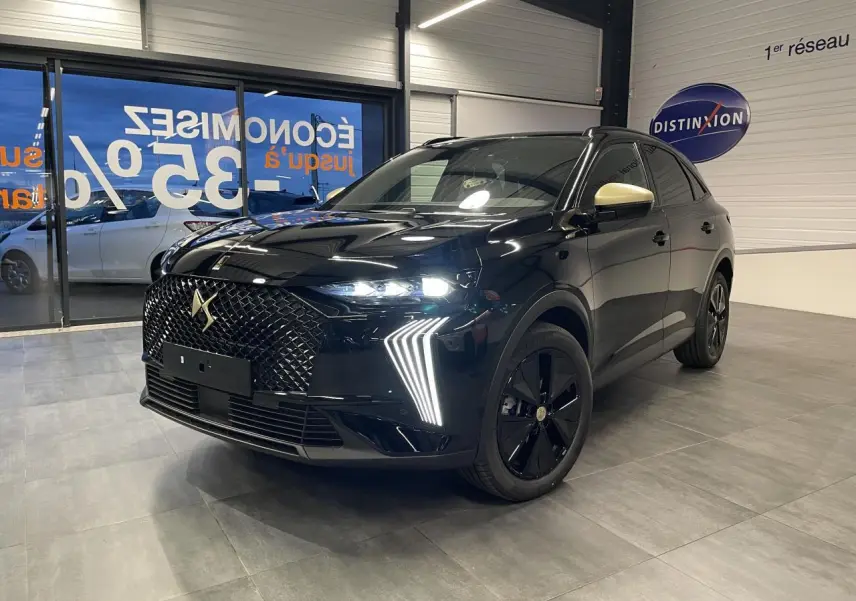 DS7 Crossback noir métallisé en 3/4 avant droit, avec calandre DS Wings et rétroviseurs couleur crème visibles en intérieur showroom.