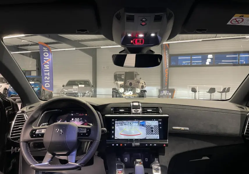 Vue intérieure avant du DS7 Crossback 2026 noir métallisé, tableau de bord Alcantara et écran tactile affichant la caméra de recul.