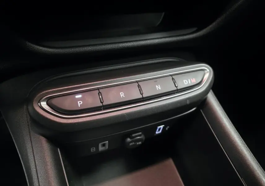 Gros plan sur la console centrale noire de la Fiat 600 Hybrid 2024 avec boutons de sélection de boîte auto éclairés.