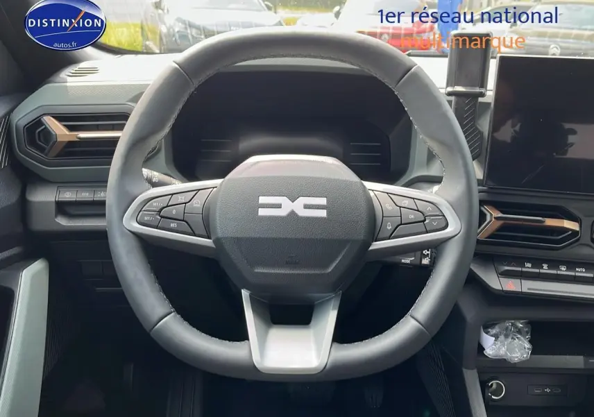 Vue centrée sur le volant multifonction du Dacia Duster 2025 avec tableau de bord et écran tactile noir.