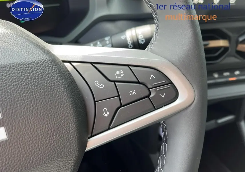 Gros plan sur les commandes multifonctions à droite du volant noir du Dacia Duster 2025, intérieur moderne et épuré.