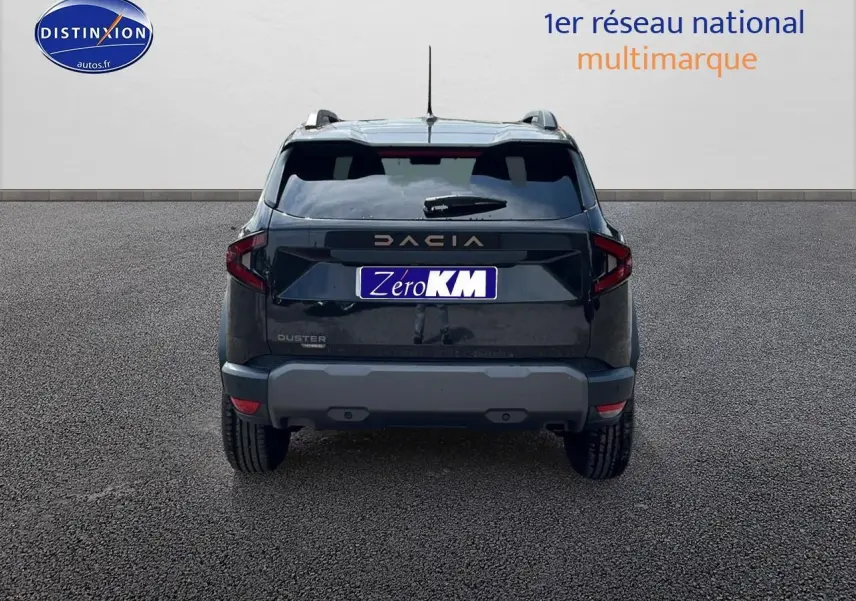 Vue arrière du Dacia Duster noir 2025 avec barres de toit et becquet, sur fond neutre gris.