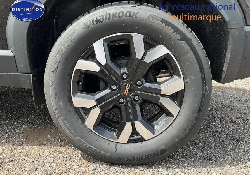 Gros plan sur la jante alu noire et argentée du côté gauche d'un Dacia Duster noir 2025.