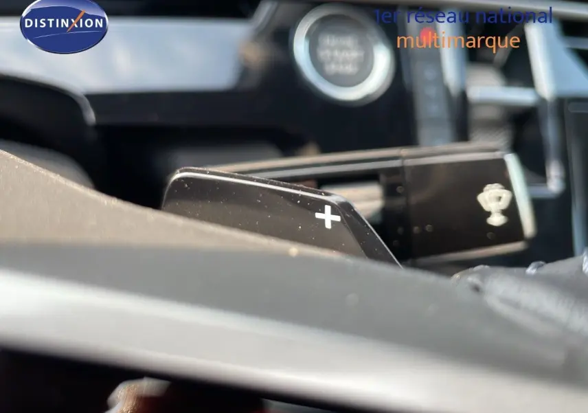 Gros plan sur la palette de changement de vitesse "+" du volant d'un Peugeot 3008 Hybrid gris artense métal.