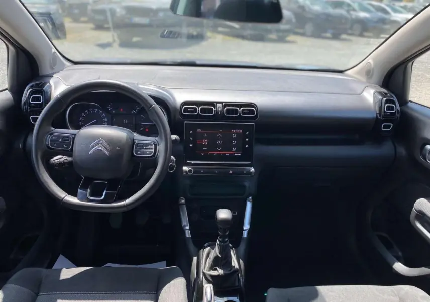 Vue intérieure avant du Citroën C3 Aircross 2023, tableau de bord noir avec volant multifonction et écran tactile central.