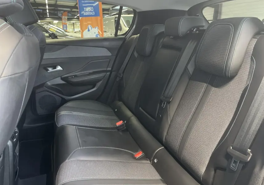 Vue intérieure côté droit des sièges arrière en sellerie tri matières noire avec surpiqûres bleues d'une Peugeot 308 2022.
