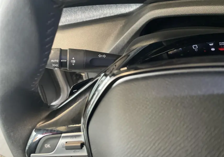 Détail du volant en cuir noir avec commandes intégrées et manette de clignotants sur Peugeot 308 gris Artense.