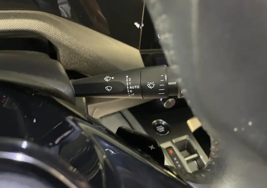 Gros plan sur la commande d'essuie-glace à gauche du volant en cuir de la Peugeot 308 gris Artense 2022.