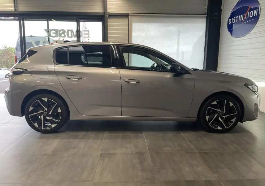 Peugeot 308 gris Artense vue de profil côté gauche, avec jantes alliage 17 pouces et poignées couleur carrosserie.