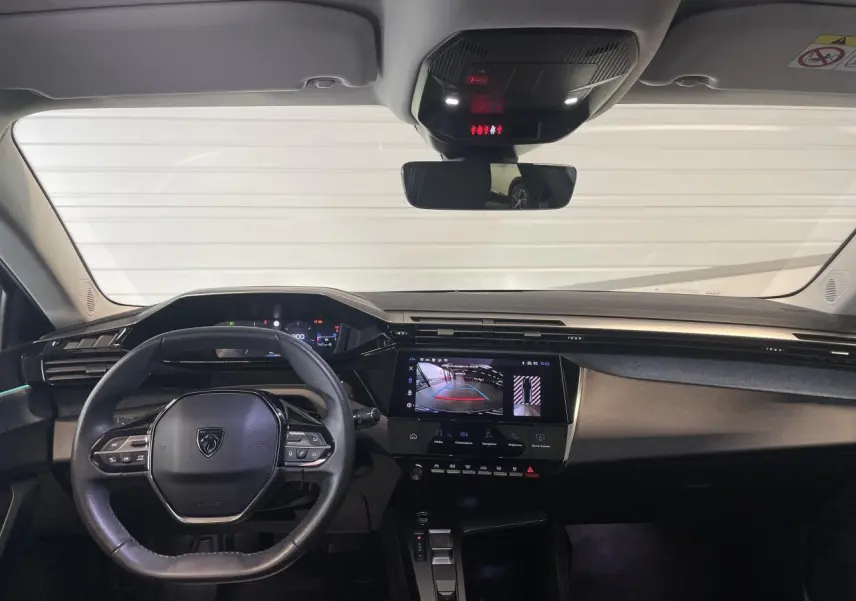 Vue intérieure avant du poste de conduite de la Peugeot 308 gris Artense avec écran tactile affichant la caméra de recul.