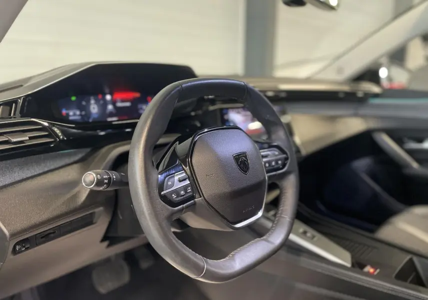Vue rapprochée du volant cuir noir et du tableau de bord numérique de la Peugeot 308 gris Artense 2022.