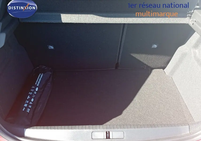 Coffre ouvert d'une Opel Corsa rouge Kardio métal avec toit noir, montrant un espace de rangement propre et un kit de sécurité.