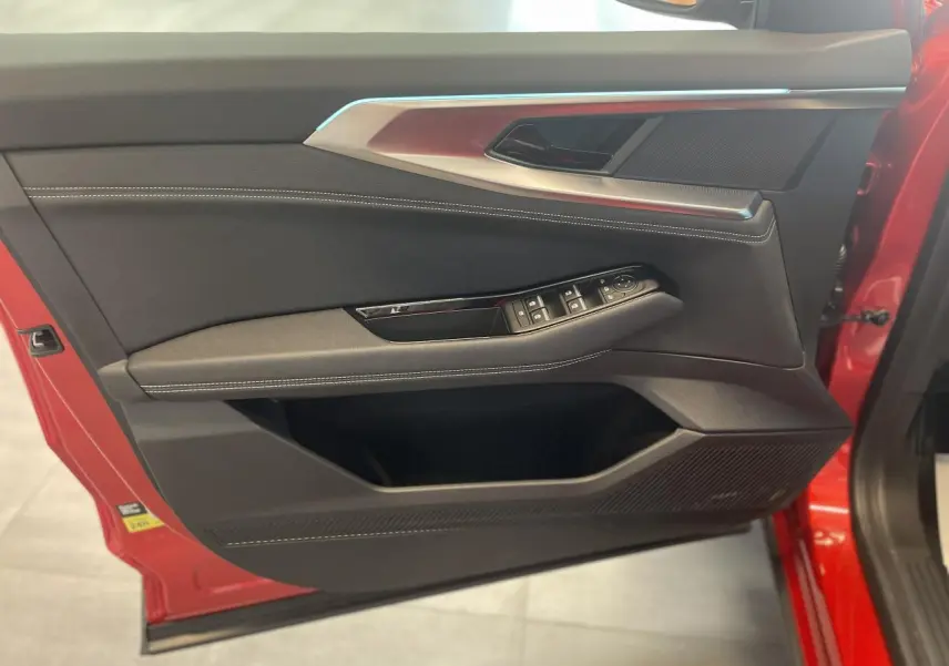 Porte avant gauche ouverte de la Renault Rafale rouge, montrant les commandes de vitres et le revêtement textile noir avec surpiqûres blanches.