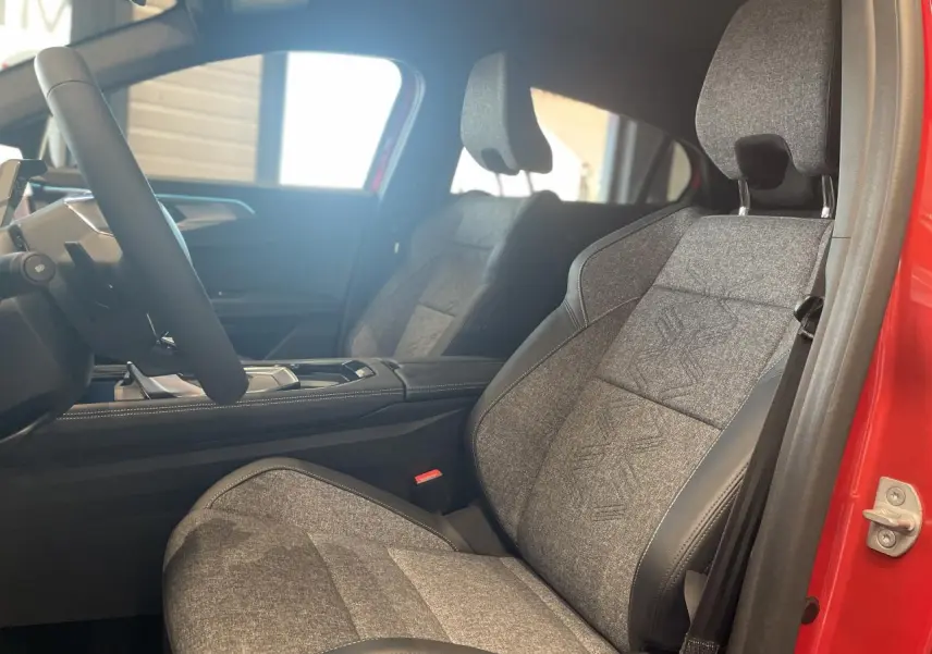 Vue intérieure côté conducteur de la Renault Rafale 2025 rouge, sièges sport gris textile avec surpiqûres argentées.