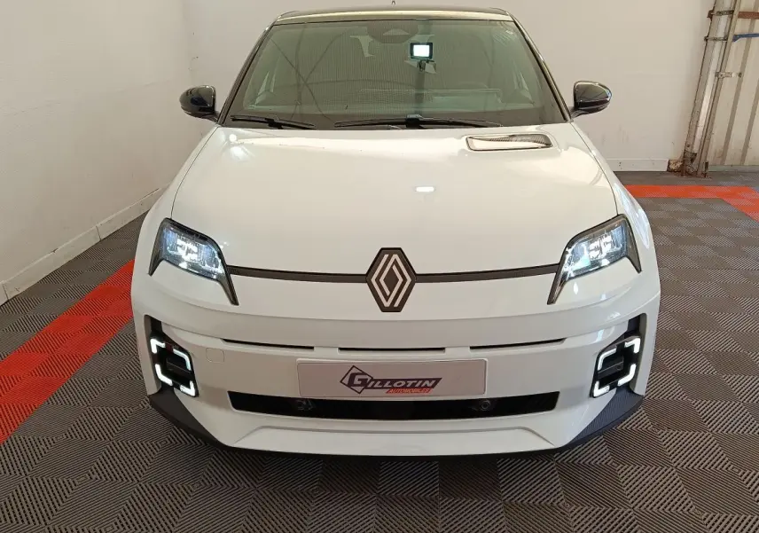 Vue avant d'une Renault R5 Techno électrique blanche avec phares LED allumés et détails noirs contrastants.
