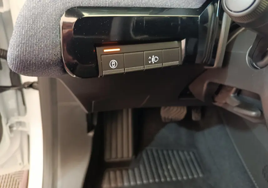 Vue intérieure côté conducteur de la Renault R5 Techno blanche 2025, avec commandes de réglage des phares et verrouillage.