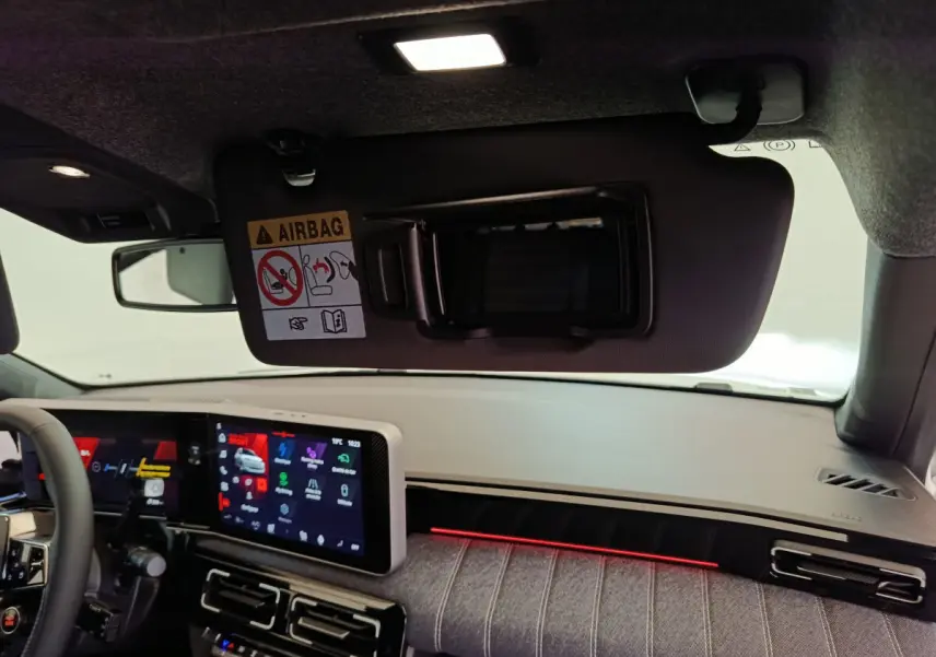 Intérieur avant droit de la Renault R5 Techno 2025, tableau de bord clair avec écran tactile et éclairage d’ambiance rouge.