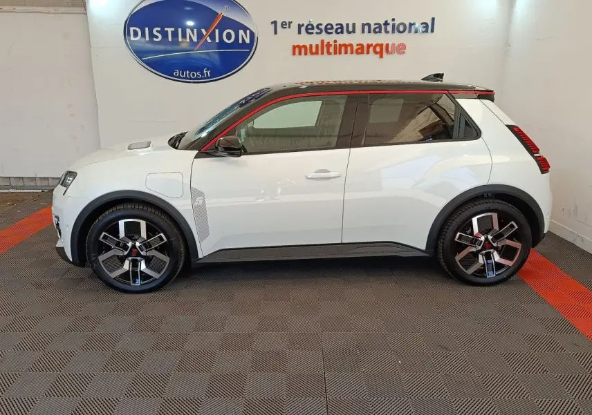 Profil droit d'une Renault R5 Techno 150 ch blanche avec jantes noires et toit noir souligné de rouge.