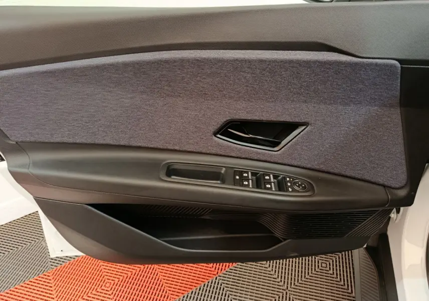 Vue rapprochée de la porte avant gauche blanche de la Renault R5 Techno 2025 avec garniture tissu gris et commandes électriques.