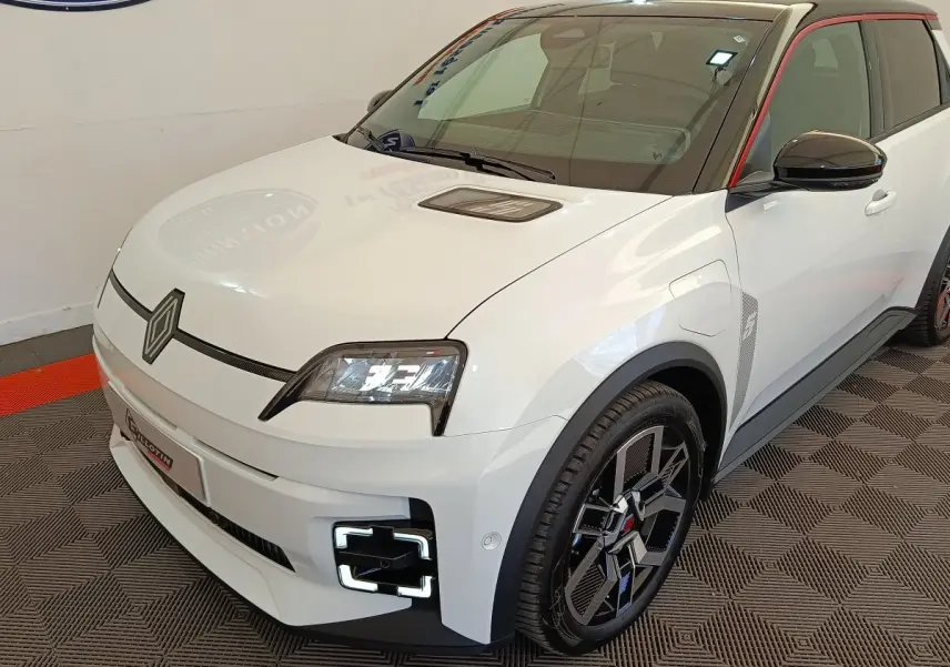 Vue 3/4 avant droite d'une Renault R5 Techno électrique blanche avec détails noirs et toit contrasté rouge.