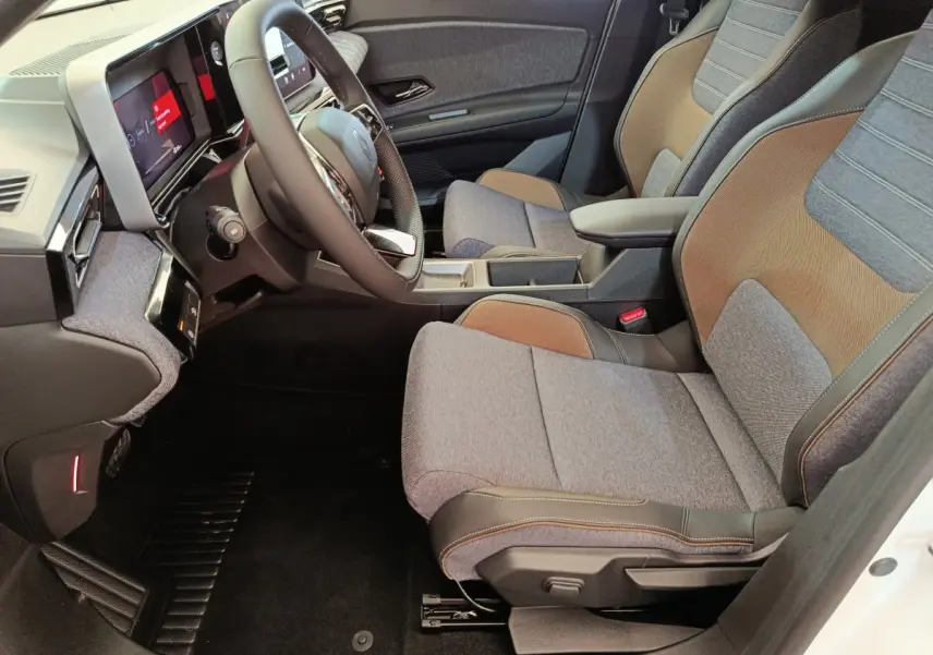 Vue intérieure côté conducteur de la Renault R5 Techno 2025, sièges tissu gris et brun avec volant multifonctions.