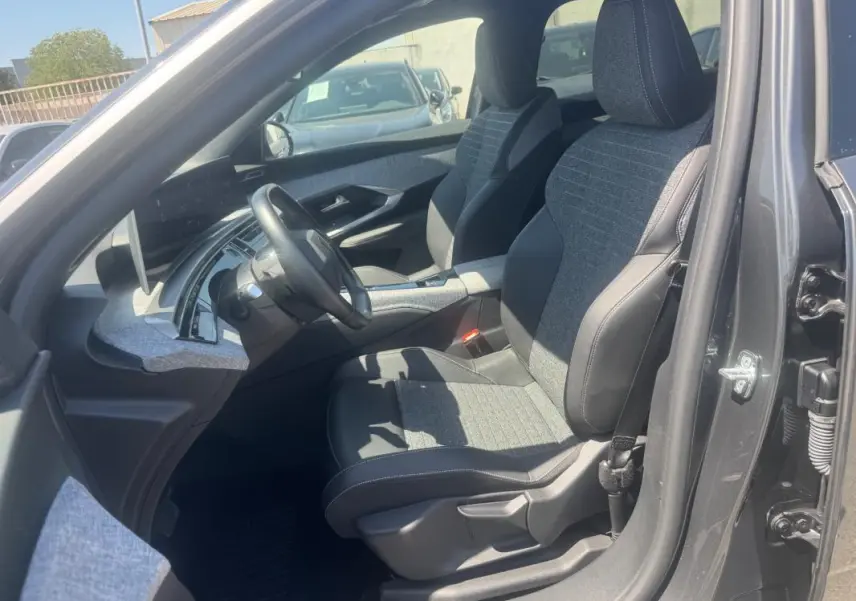 Vue intérieure côté conducteur du Peugeot 5008 Hybrid gris 2025, mettant en valeur les sièges bi-matière et le tableau de bord moderne.