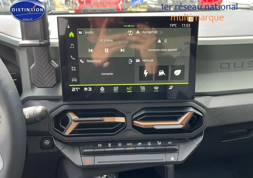 Tableau de bord du Dacia Duster 2025 avec écran tactile et aérateurs hexagonaux couleur bronze.