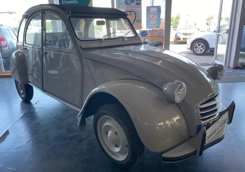 Citroën 2 CV beige clair refaite à neuf vue 3/4 avant gauche dans un garage lumineux.