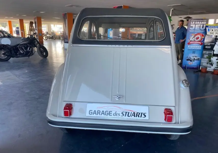 Vue arrière d'une Citroën 2 CV beige clair de 1968 refaite à neuf, avec feux rouges et toit ouvrant visible.