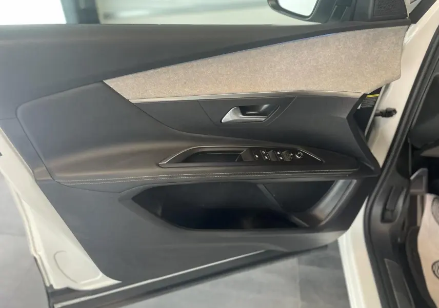 Porte avant gauche ouverte d'un Peugeot 3008 blanc nacré, montrant garniture noire et grise avec commandes électriques.