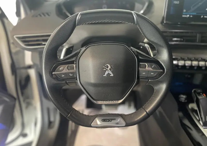 Volant cuir perforé Peugeot 3008 GT vu de face avec badge GT et commandes intégrées visibles.