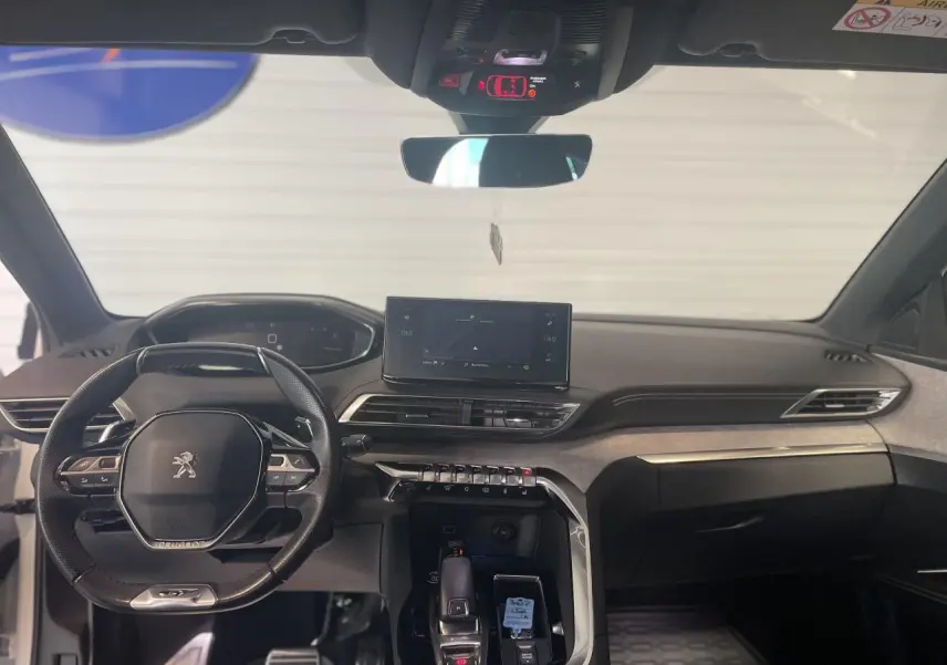 Intérieur avant du Peugeot 3008 blanc nacré 2022, tableau de bord moderne avec écran tactile et volant compact noir.
