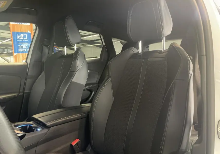 Gros plan sur les sièges avant noirs du Peugeot 3008 GT 2022, avec accoudoir central et coutures contrastées.
