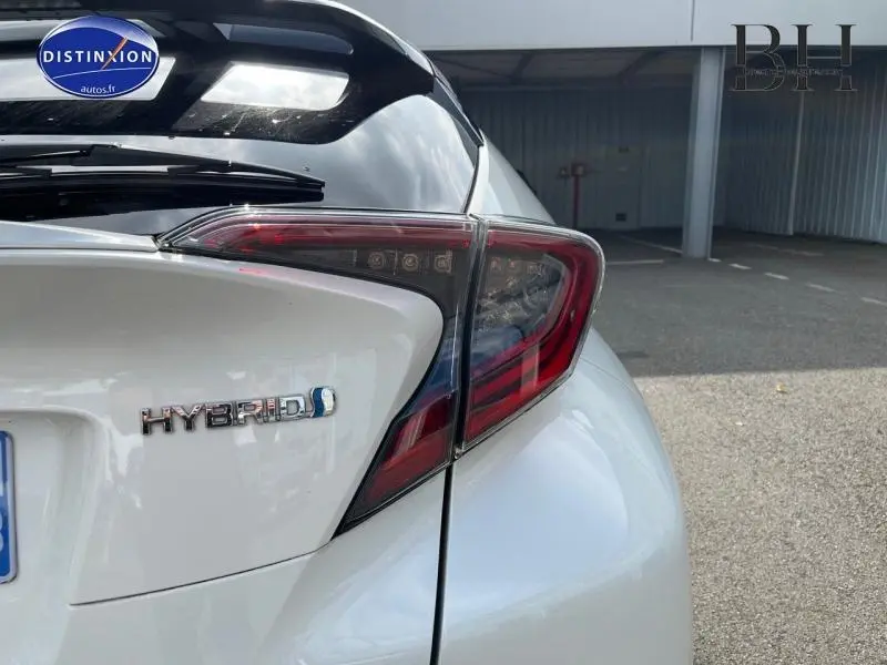 Gros plan sur l'arrière droit blanc nacré du Toyota C-HR 122h avec feu LED et badge Hybrid visible.