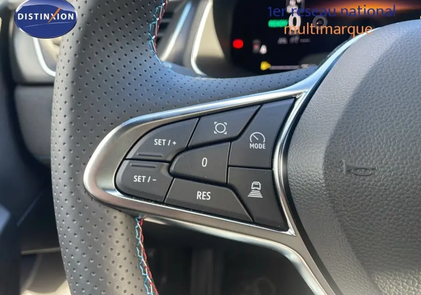 Gros plan sur les commandes de régulateur de vitesse au volant en cuir perforé du Renault Captur E-Tech Gris Rafale toit noir.