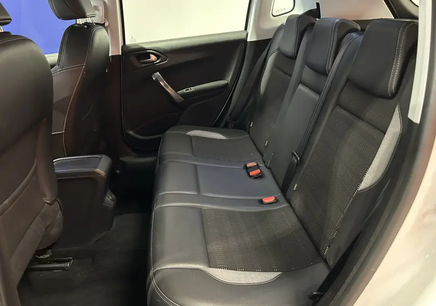 Vue intérieure côté droit des sièges arrière en cuir noir du Peugeot 2008 blanc, avec appuie-têtes et ceintures visibles.