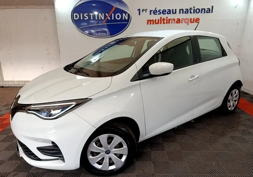 Renault ZOE Business R110 blanc vue 3/4 avant droit en intérieur avec phares LED et jantes acier.